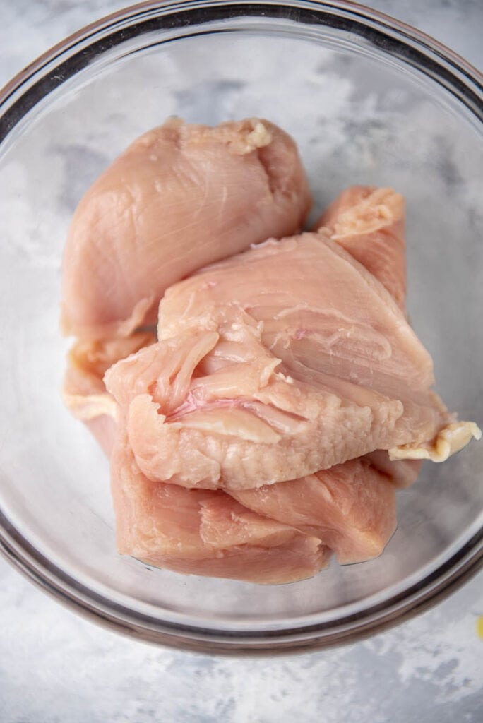 glass bowl with raw chicken breasts