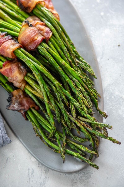 bacon wrapped grilled asparagus bundles on a gray platter