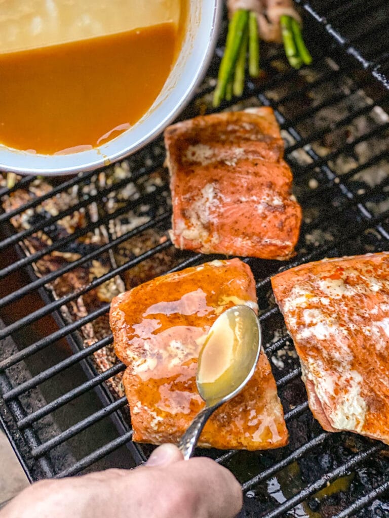 spooning sauce over salmon on grill