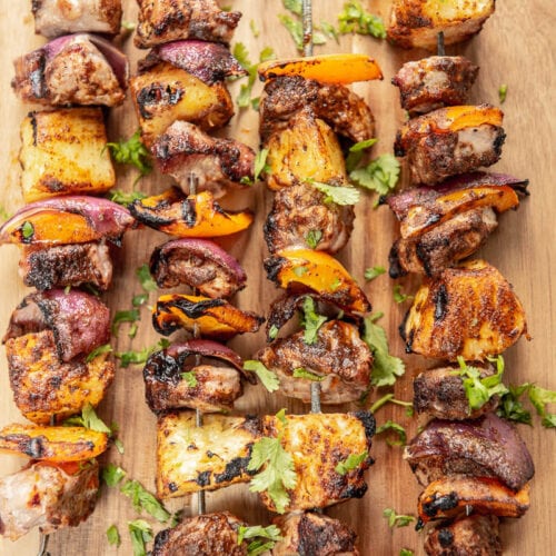 4 pork and veggie skewers on a wood board