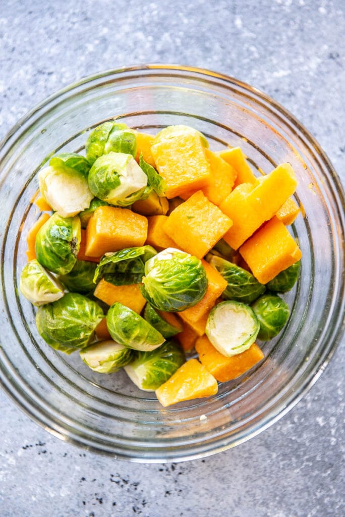 brussels sprouts and cubed butternut squash in a glass bowl