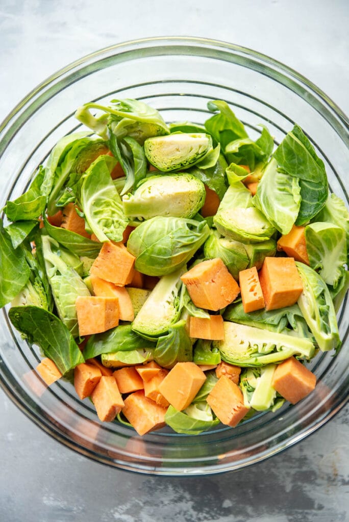 chopped sweet potatoes and brussels sprouts in a glass bowl