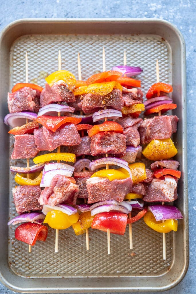 raw steak kebabs on a grill pan